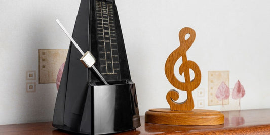 Classic metronome beside a wooden music note decoration on a tabletop.