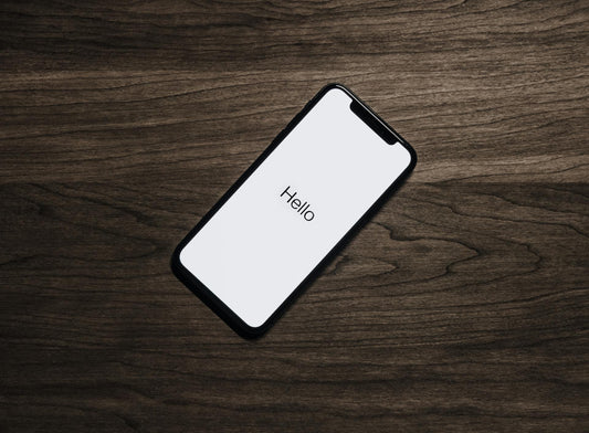 Iphone on a wood table with the word "Hello" on the screen