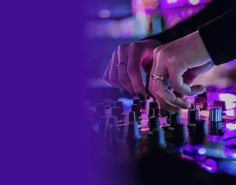 Close-up of hands adjusting controls on a DJ mixing board with purple neon lighting.