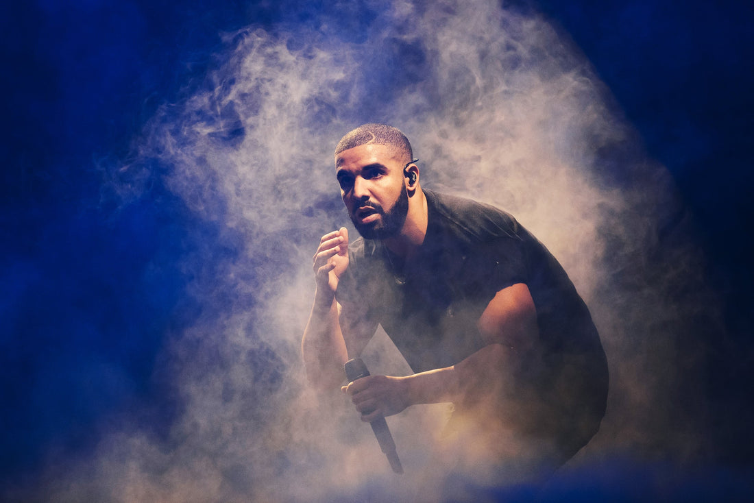 Drake in the midst of smoke holding a microphone on stage