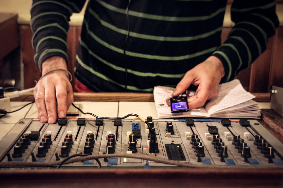 Recording engineer adjusting audio levels on a mixing console in a studio setting.