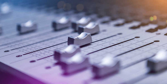 Close-up of an audio mixing console with volume faders and studio controls.