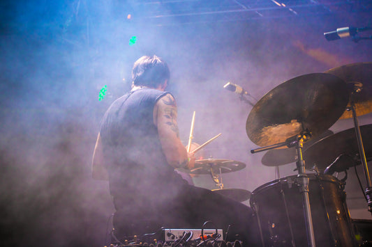 A drummer performing on stage through haze and lights, capturing a raw live music energy.