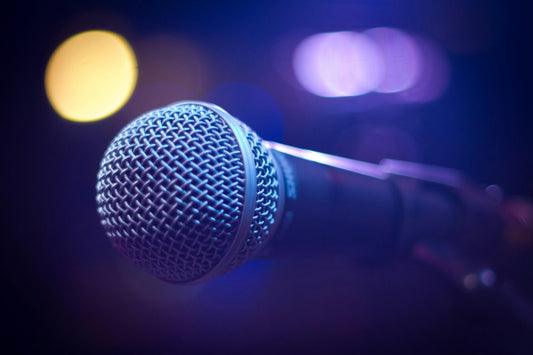 A close-up microphone under stage lights, capturing a vibrant live performance atmosphere.
