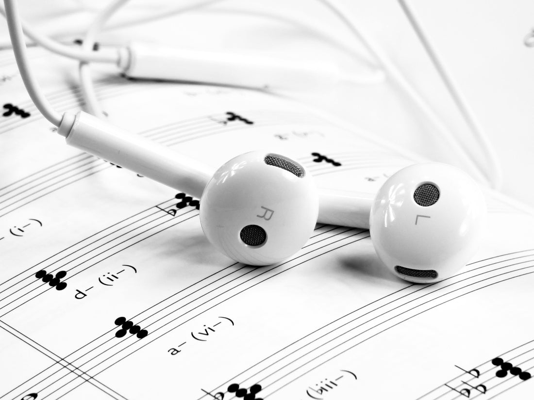 White earbuds resting on sheet music, blending modern listening with classical composition.