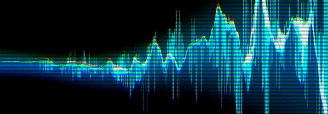 A colorful digital audio waveform displayed on a dark background, with bright blue and green frequency peaks and scanline effects.