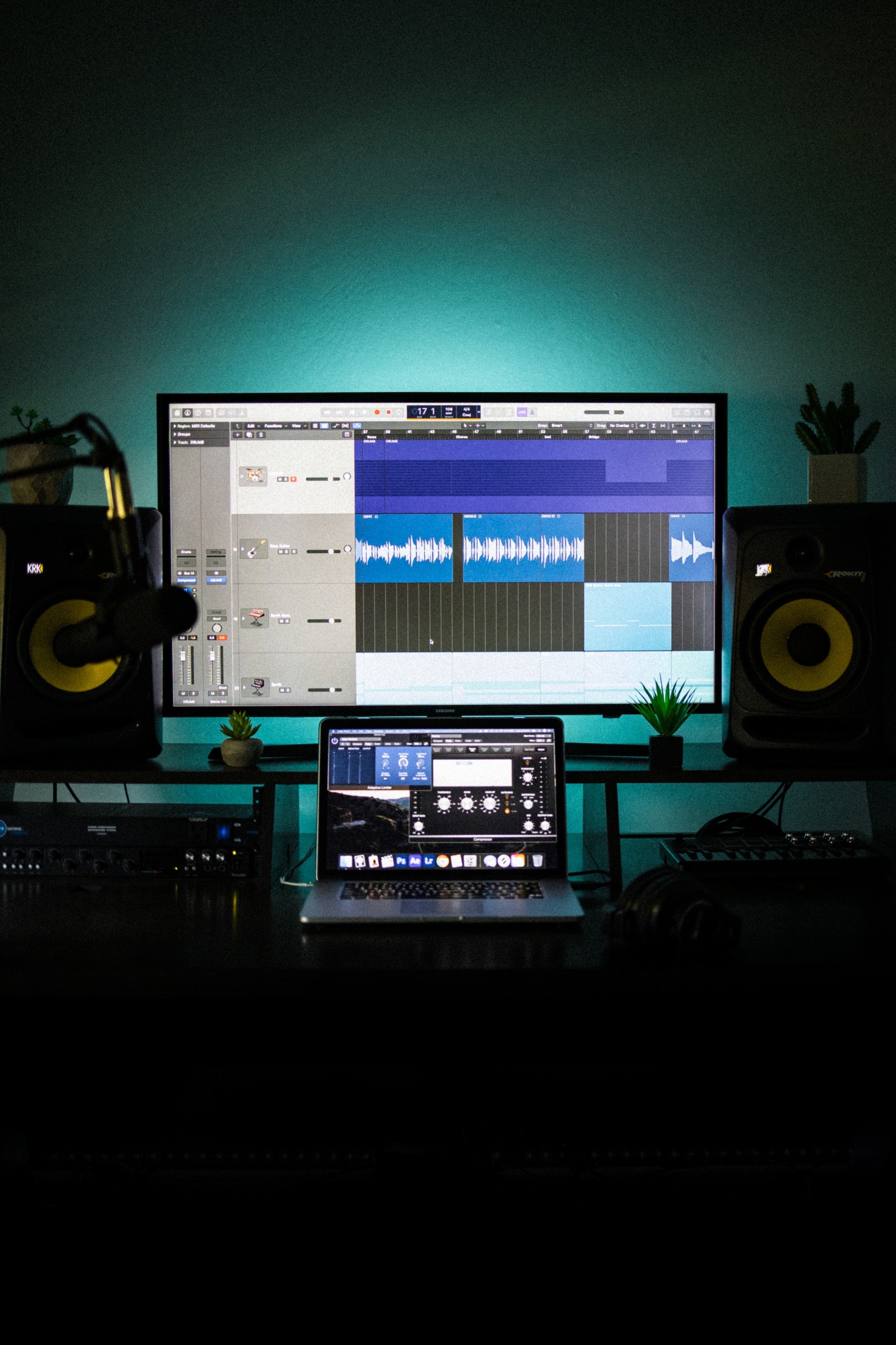 Logic pro software open on a macbook and a monitor behind it in a studio
